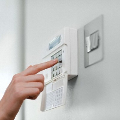 Woman setting burglar alarm